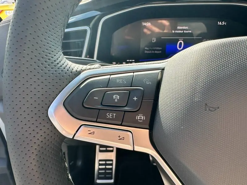 Gros plan sur les commandes du volant cuir perforé côté gauche du Volkswagen T-Roc 2025 avec affichage numérique au tableau de bord.