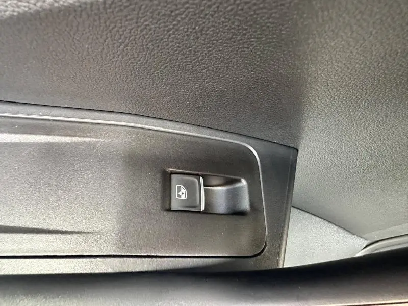 Bouton de commande de lève-vitre noir sur la porte intérieure d'un Volkswagen T-Roc 2025.