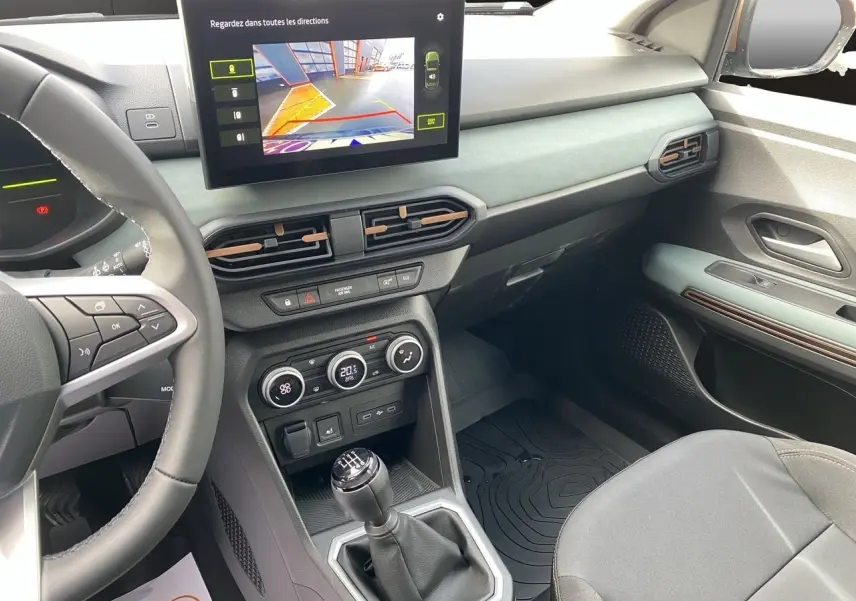 Vue intérieure côté conducteur de la Dacia Sandero Stepway 2026, montrant la console centrale avec écran tactile et levier de vitesse manuel.