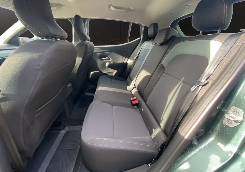 Vue côté droit des sièges arrière en tissu gris noir du Dacia Sandero Stepway Vert Cèdre avec porte ouverte.