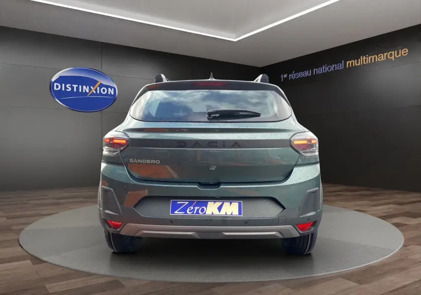 Vue arrière d'une Dacia Sandero Stepway 2026 en Vert Cèdre, avec feux allumés et plaque Zero KM visible.