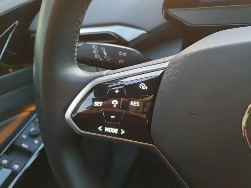 Gros plan sur les commandes de régulateur de vitesse au volant noir du Volkswagen ID.4 2023, finition Life Plus.