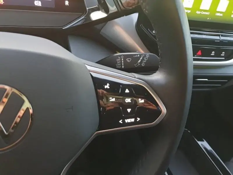 Gros plan sur le volant multifonction noir du Volkswagen ID.4 2023 avec commandes tactiles et tableau de bord partiel visible.