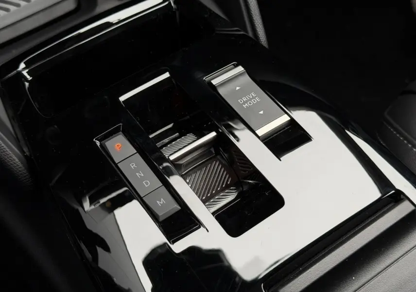 Gros plan sur la console centrale noire brillante de la Citroën C4 Hybrid 2025 avec sélecteur de vitesses et bouton Drive Mode.
