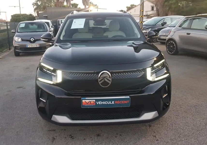 Citroën C3 noir vue de face avec feux LED allumés et barres de toit visibles sur un parking extérieur.