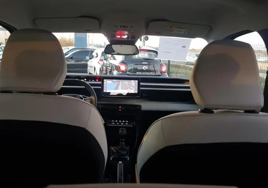 Vue intérieure arrière de la Citroën C3 2025 noire, montrant les sièges bicolores et l'écran tactile central.