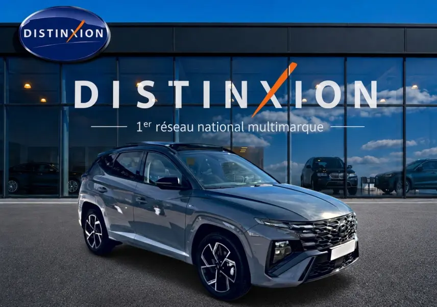Hyundai Tucson 2026 gris shadow en 3/4 avant droit, avec calandre noire et jantes alu distinctives.