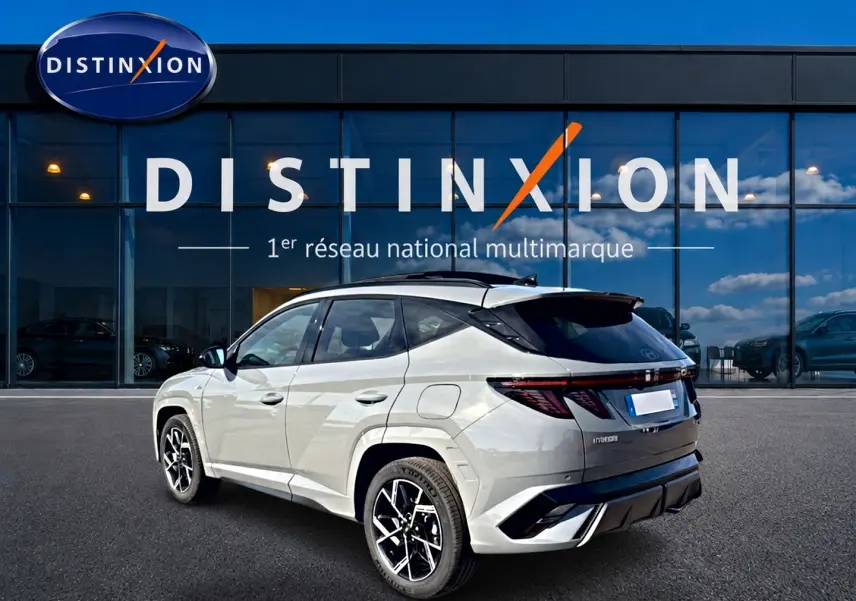 Vue 3/4 arrière droite du Hyundai Tucson gris shadow avec jantes alu noires devant une vitrine Distinxion.
