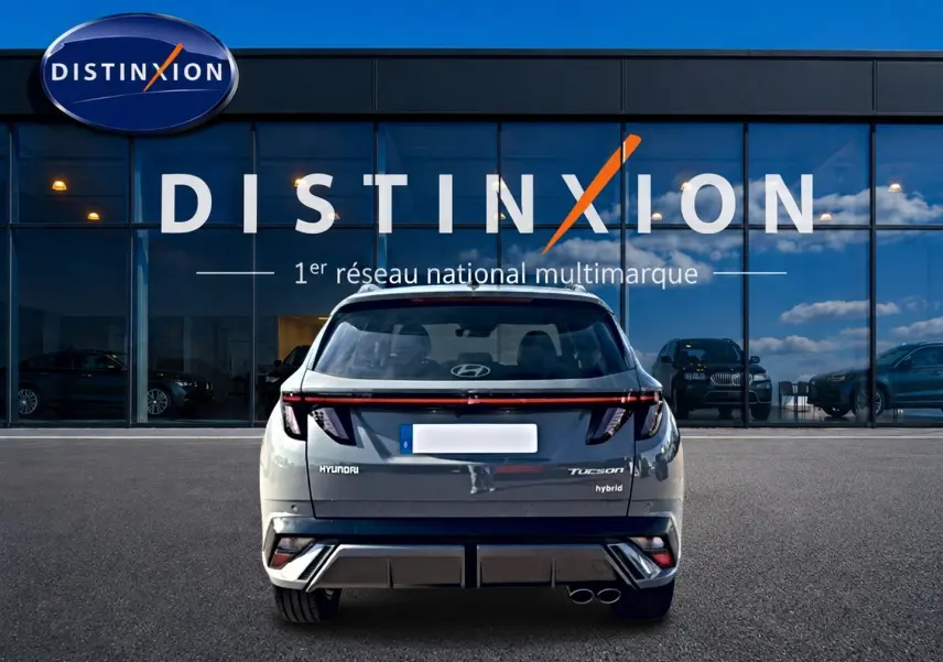 Vue arrière d'un Hyundai Tucson gris shadow hybride, avec feux arrière LED et double sortie d'échappement visible.