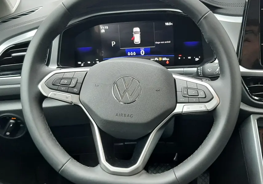 Vue rapprochée du volant noir du Volkswagen T-Roc 2025 avec tableau de bord numérique et commandes intégrées.