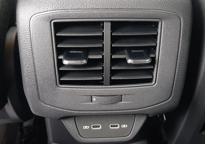Détail des aérateurs arrière noirs avec deux ports USB-C sur la console centrale du Volkswagen T-Roc gris pyrite.