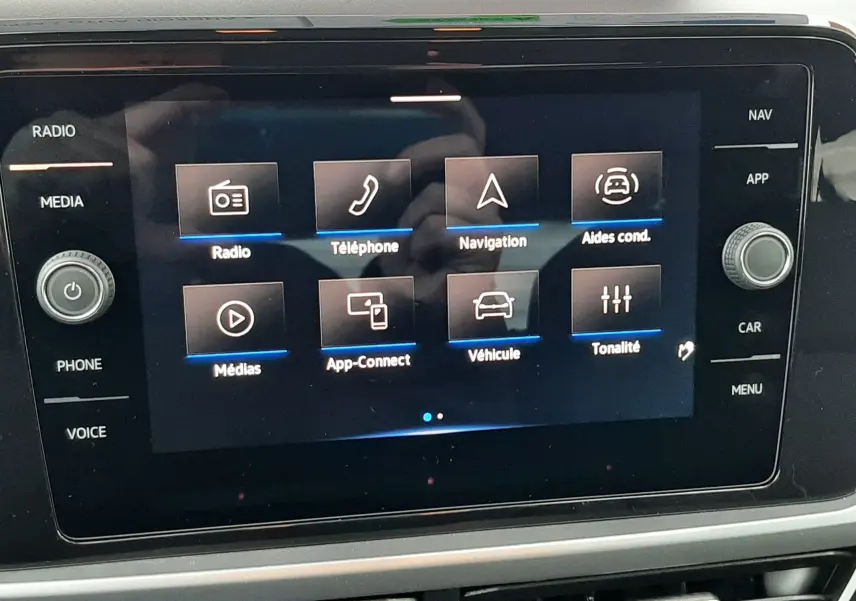 Écran tactile central du Volkswagen T-Roc gris pyrite 2025 affichant les options radio, téléphone, navigation et aides à la conduite.