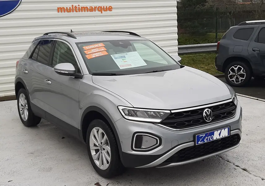 Volkswagen T-Roc gris pyrite métal vue 3/4 avant droit, avec calandre noire et jantes argentées.