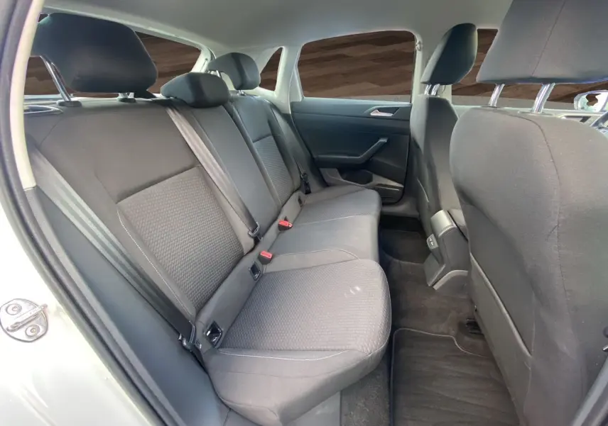 Vue intérieure arrière côté gauche de la Volkswagen Polo blanche, montrant les sièges arrière en tissu noir et les ceintures de sécurité.