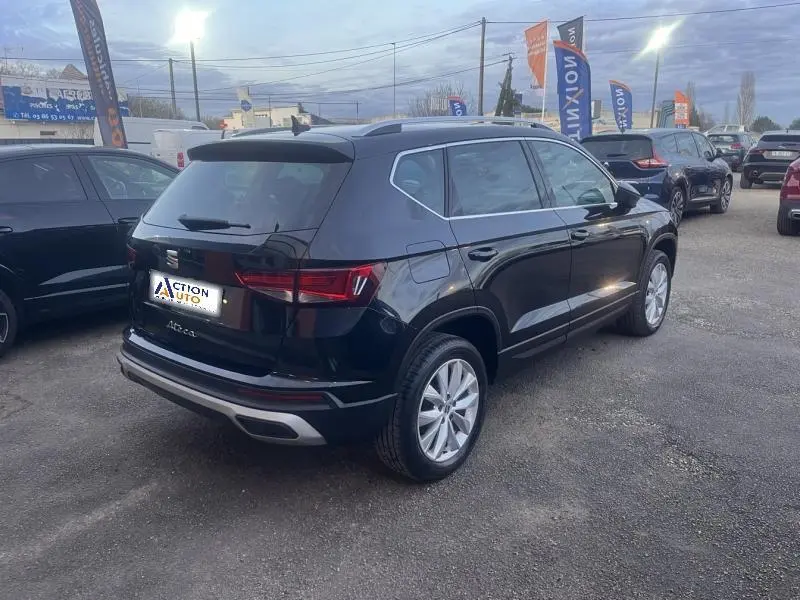 Vue 3/4 arrière droite d’un SUV SEAT Ateca noir métallique avec jantes alliage et vitres surteintées, stationné en extérieur.