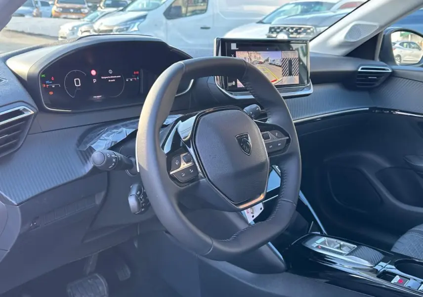 Vue intérieure côté conducteur du Peugeot 208 Hybrid 110 e-DCS6 Allure 2025, avec volant multifonction et écran tactile.