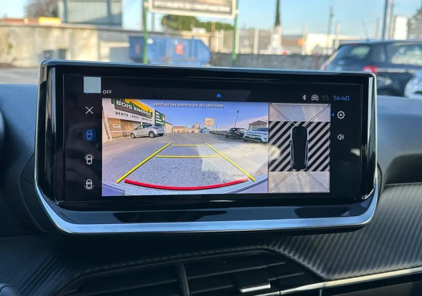 Écran tactile intérieur montrant la caméra de recul et vue 360° du Peugeot 208 blanc, tableau de bord moderne.