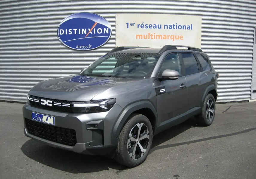 Dacia Bigster gris schiste en 3/4 avant droit, SUV hybride avec calandre noire et jantes modernes.