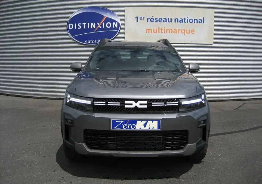 Vue de face du Dacia Bigster gris schiste 2026 avec calandre noire et phares LED allumés.