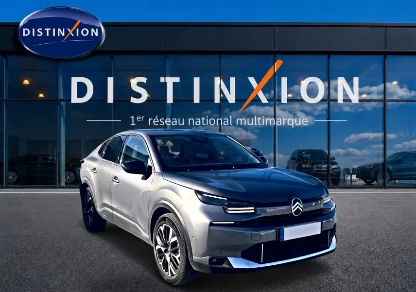 Citroën C4 X gris mercure vue 3/4 avant, avec calandre distinctive et jantes alliage devant showroom Distinxion.
