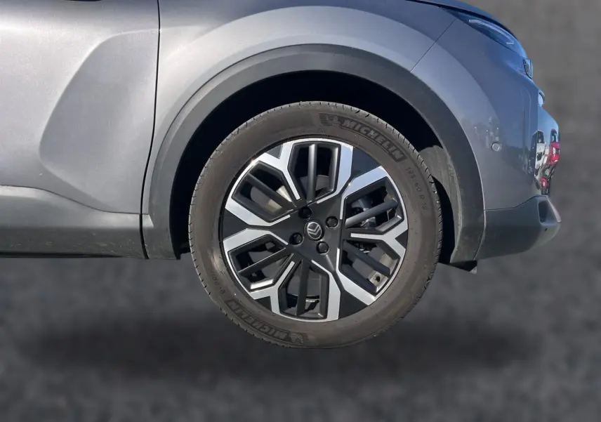 Gros plan sur la roue arrière droite et la jante alu bicolore du Citroën C4 X gris mercure, partie arrière visible.
