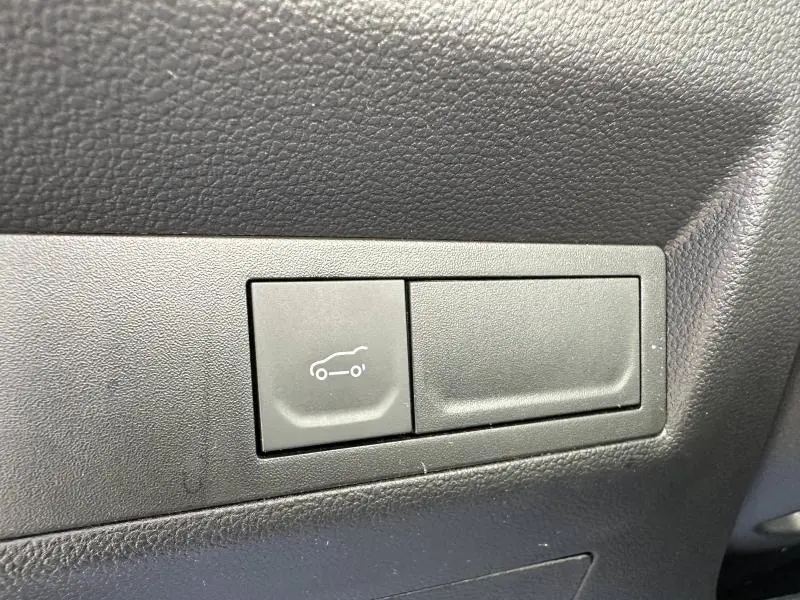 Détail intérieur montrant le bouton d'ouverture électrique du coffre sur panneau noir du Renault Symbioz rouge 2025.