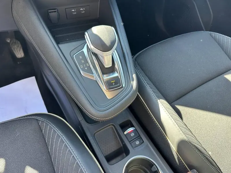 Vue rapprochée de la console centrale noire avec levier de vitesse automatique et siège tissu côté droit du Renault Symbioz rouge.
