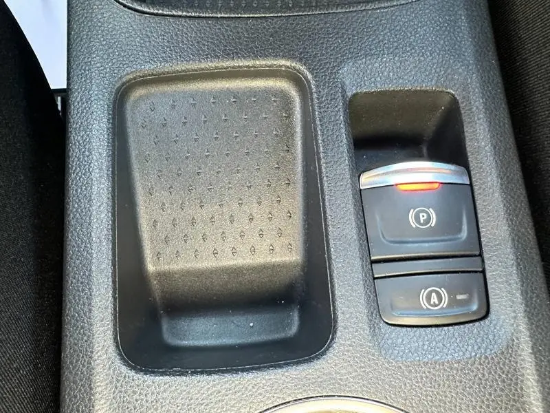 Gros plan sur la console centrale noire du Renault Symbioz avec boutons de frein à main électronique et arrêt auto. moteur.