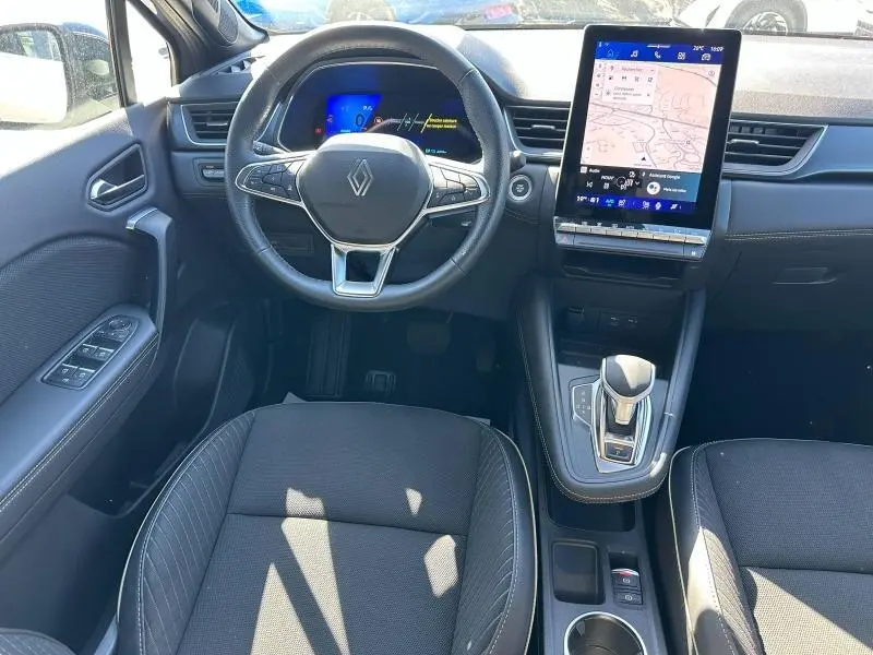 Vue intérieure avant centrée sur le volant multifonction Renault avec écran tactile vertical et sièges noirs.
