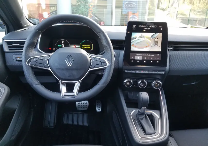 Vue intérieure avant du tableau de bord de la Renault Clio V hybride avec écran tactile et volant multifonction noir.