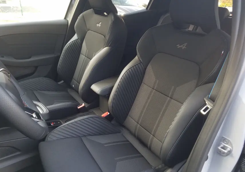 Vue intérieure des sièges avant noirs avec logo Alpine brodé sur une Renault Clio V gris Rafale, version hybride 2025.