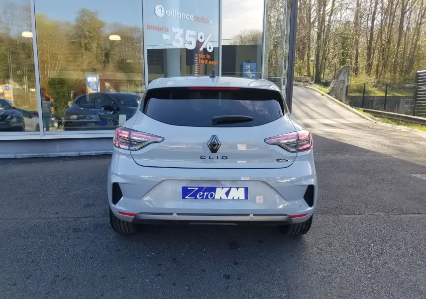 Vue arrière d'une Renault Clio V gris Rafale avec feux LED et logo distinctif sur un parking extérieur.