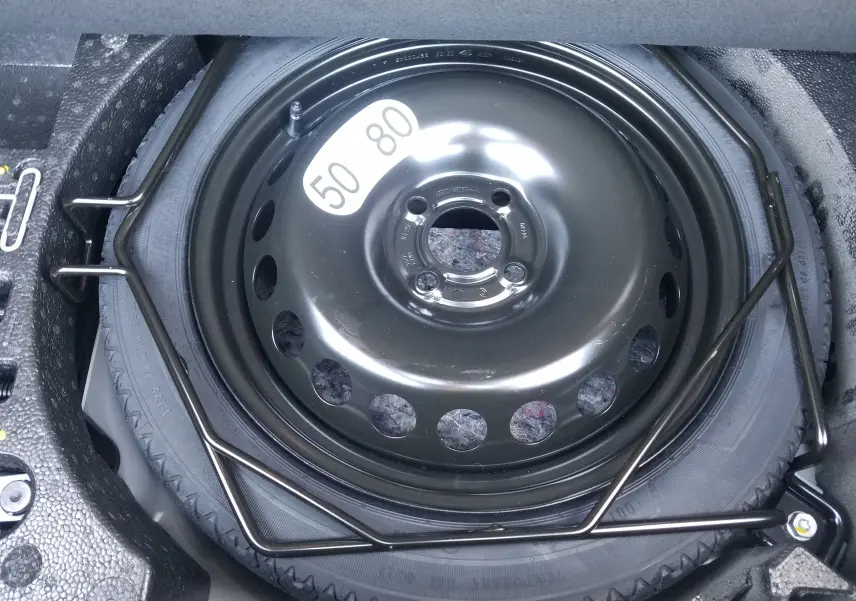 Roue de secours temporaire noire de la Renault Clio V 1.6E-TECH Hybride 145, vue en gros plan dans le coffre.