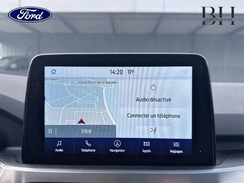 Écran tactile central du Ford Kuga 2022 affichant la navigation et les options audio, vue intérieure frontale.
