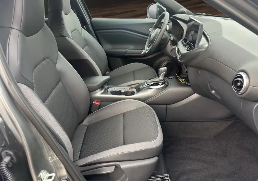 Vue intérieure côté conducteur du Nissan Juke 1.6 Hybrid 2025 gris squale, avec sièges et volant chauffants visibles.