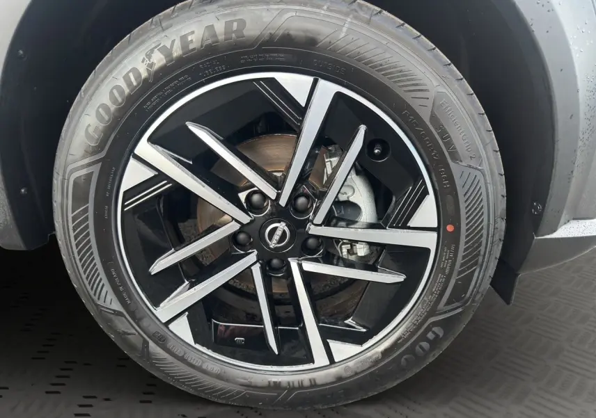 Gros plan sur la jante noire et argentée du Nissan Juke 1.6 Hybrid 2025 en gris squale, avec pneu Goodyear visible.