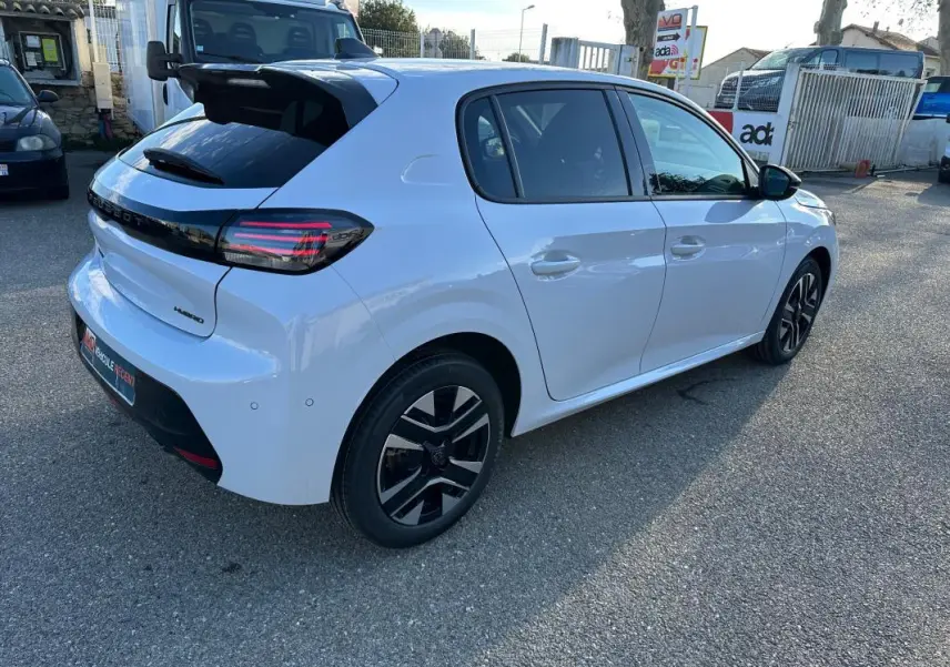 Vue 3/4 arrière droite d'une Peugeot 208 Hybrid 110 blanche avec jantes alliage noires et feux arrière LED.