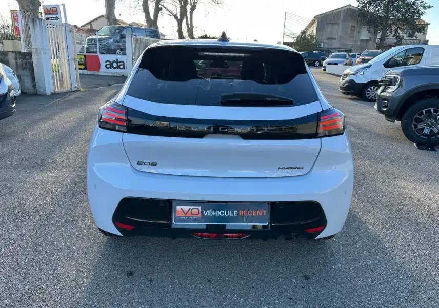 Vue arrière d'une Peugeot 208 Hybrid blanche de 2025 avec feux LED et bande noire distinctive sur le hayon.