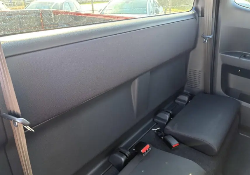 Vue intérieure arrière côté droit du pick-up Isuzu D-MAX 2026, sièges arrière rabattus en tissu noir.