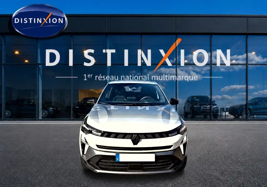 Vue frontale d'une Renault Symbioz blanc nacré, avec calandre noire et phares LED, devant une vitrine Distinxion.