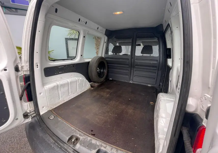 Vue intérieure arrière du Volkswagen Caddy blanc Candy 2014, montrant l'espace de chargement avec roue de secours.