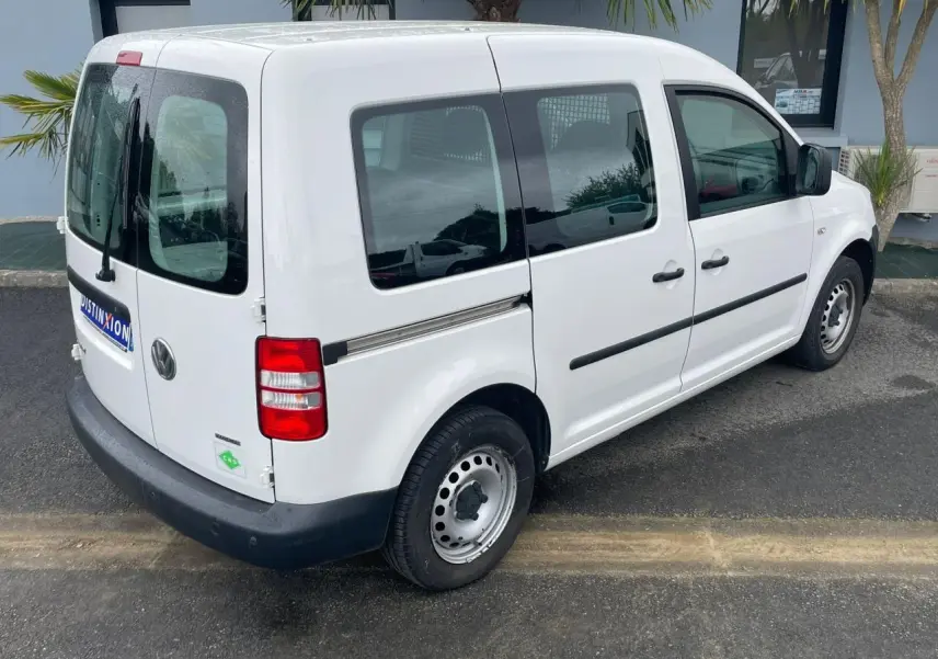Volkswagen Caddy blanc Candy vue 3/4 arrière droit avec galerie de toit et vitres teintées.