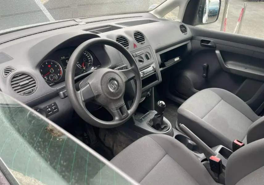 Vue intérieure côté conducteur du Volkswagen Caddy 2014, montrant le tableau de bord et la boîte manuelle.
