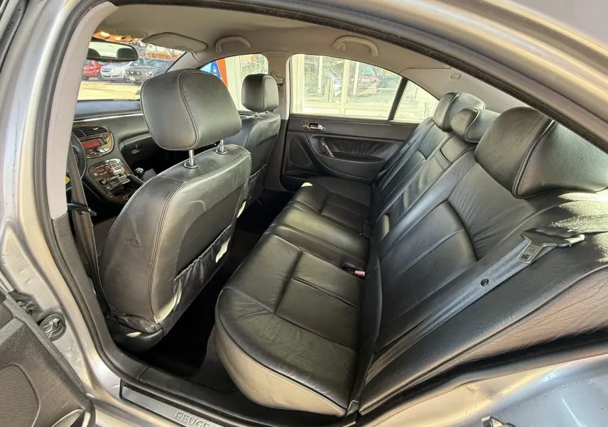 Vue intérieure arrière droite de la Peugeot 607 gris, sièges en cuir noir et tableau de bord visible à l'avant.