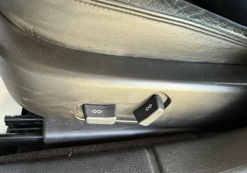 Boutons de réglage électrique des sièges en cuir noir d'une Peugeot 607, vue rapprochée du côté gauche.