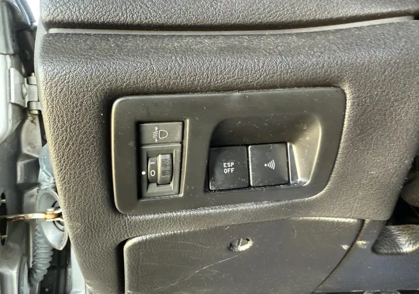 Gros plan sur les commandes noires du tableau de bord côté gauche d'une Peugeot 607 gris, avec réglage éclairage et bouton ESP off.