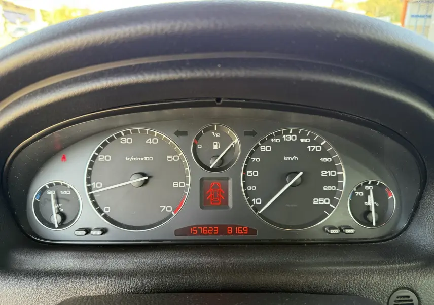 Tableau de bord de Peugeot 607 gris, affichant compteurs et jauge de carburant en gros plan.