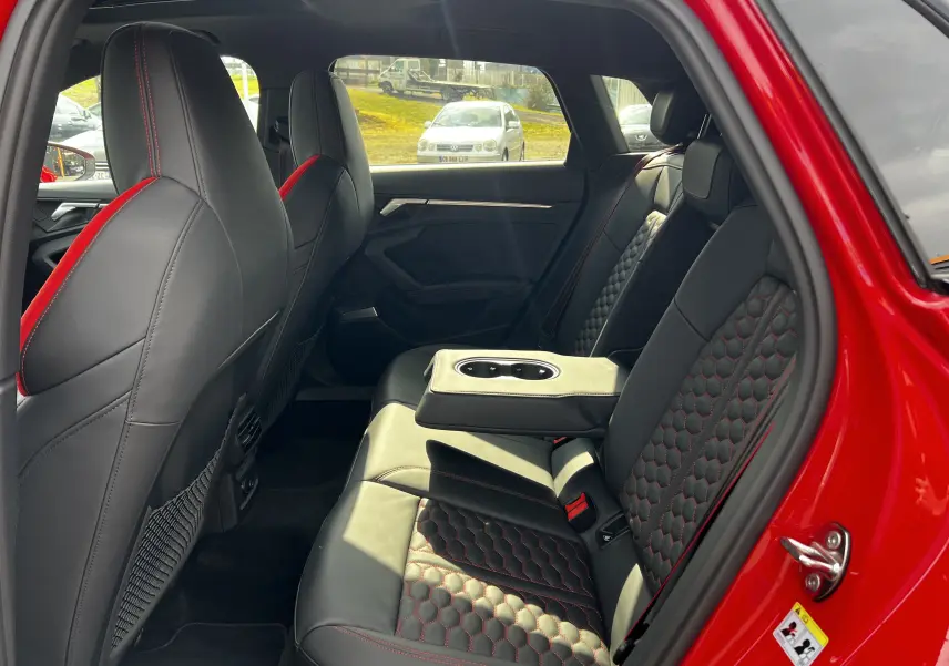 Vue intérieure arrière droite de l'Audi RS3 Sportback rouge 2022 avec sièges cuir noir à surpiqûres rouges et accoudoir central.
