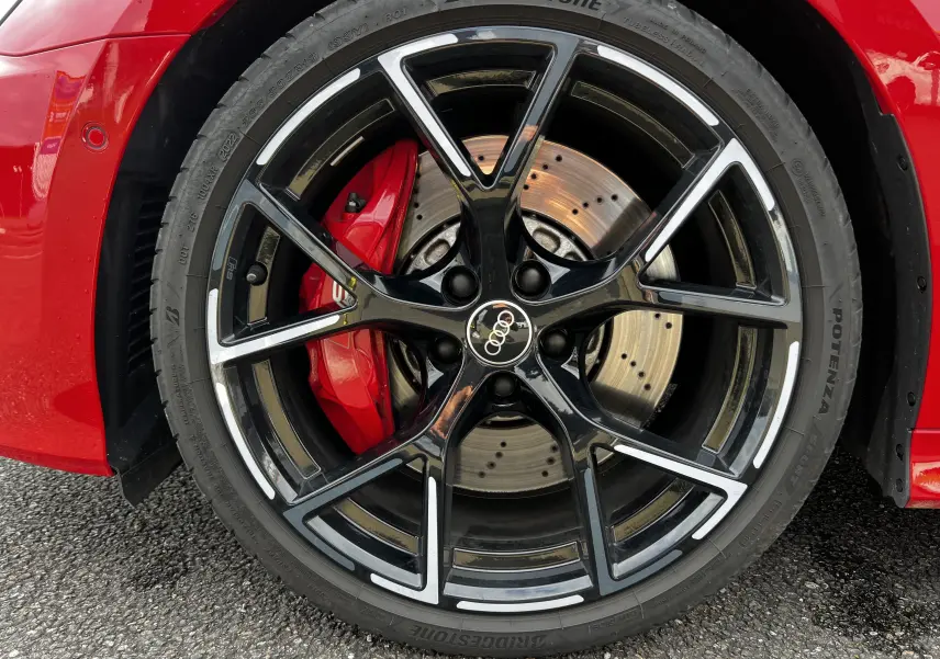 Gros plan sur la roue avant droite noire et argentée de l'Audi RS3 Sportback rouge avec étrier de frein rouge visible.