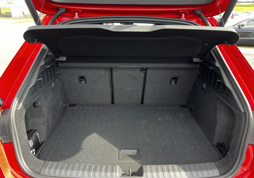 Coffre ouvert vu de l'arrière d'une Audi RS3 Sportback rouge 2022, intérieur du coffre en tissu noir.